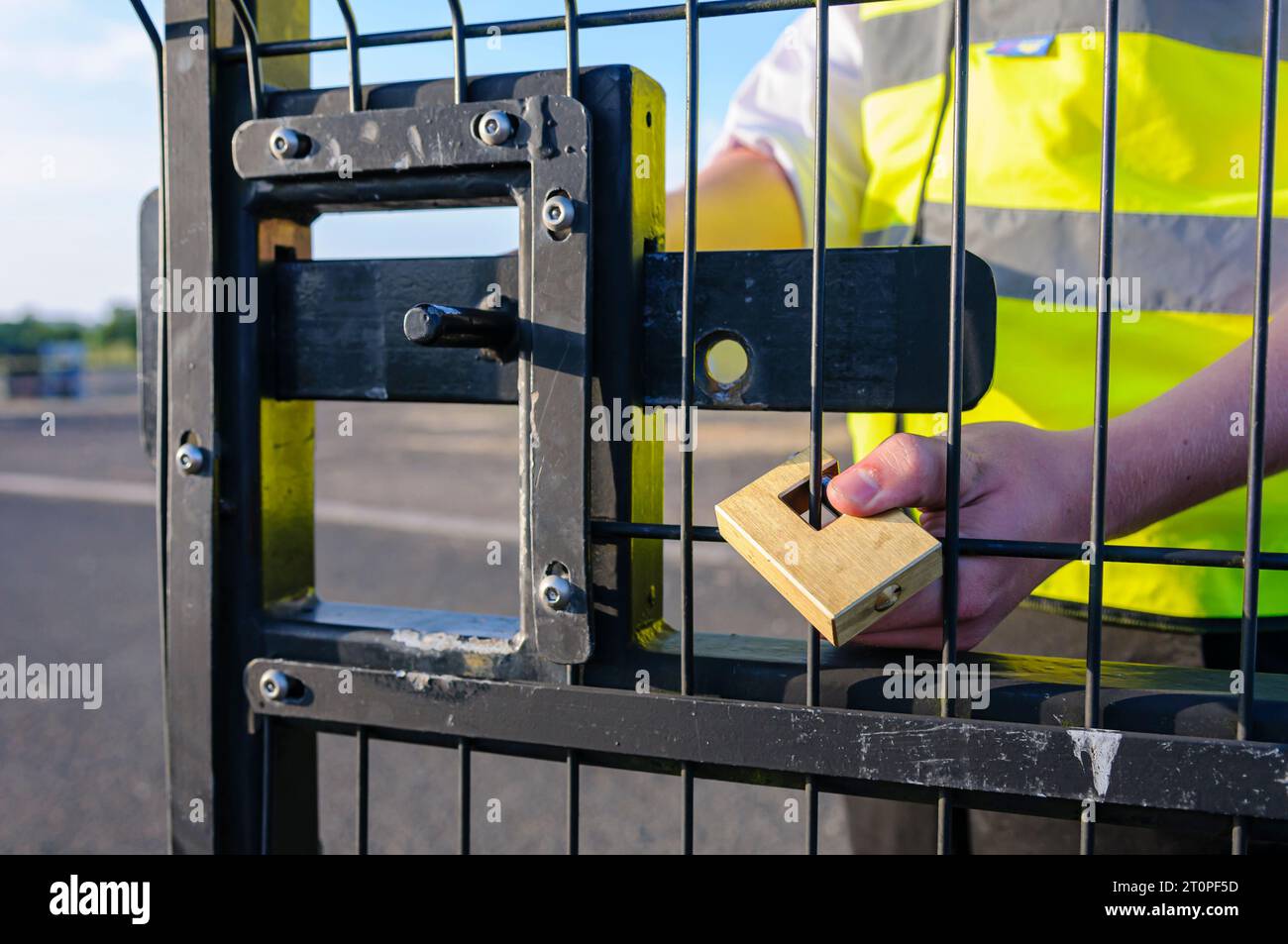 A security guard attaches a lock to a gate after unlocking the bolt and