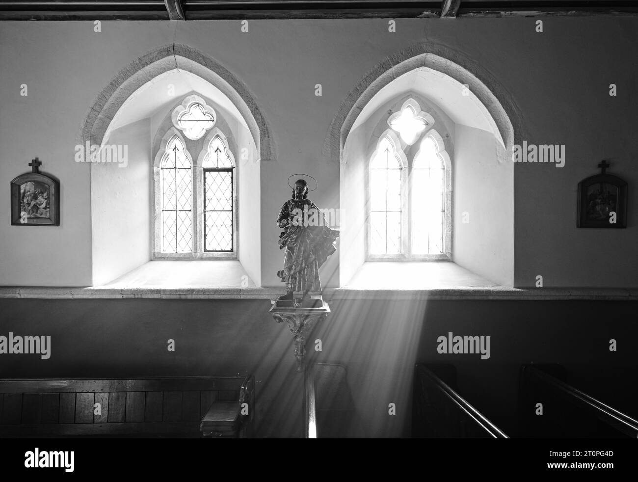ST.HILARY CHURCH SUNLIGHT STREAMING THROUGH THE WINDOW ILLUMINATING STATUE OF JESUS Stock Photo