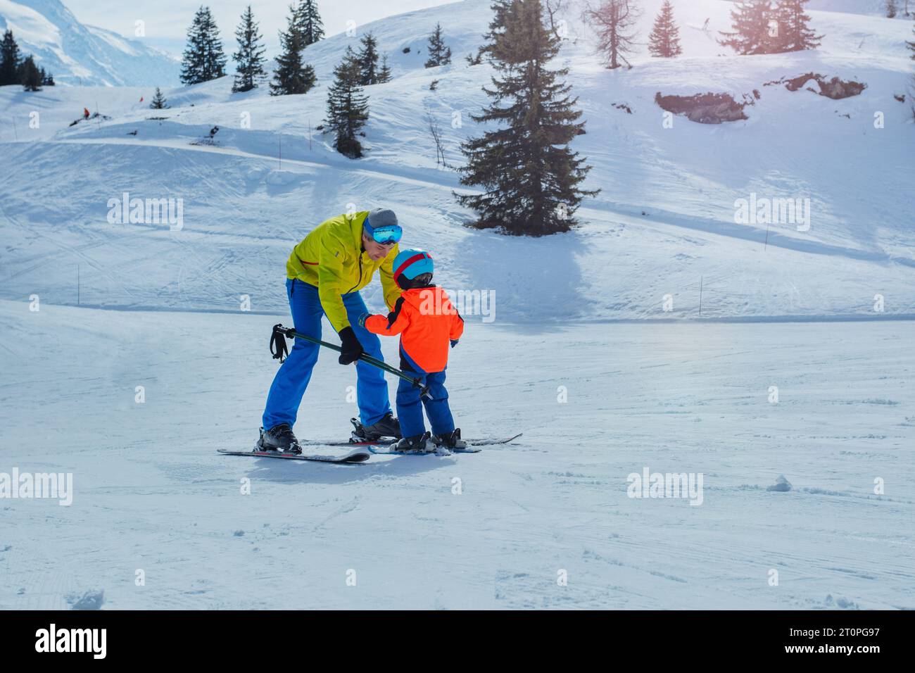 Father in skiing school glide backwards teach child to ski Stock Photo
