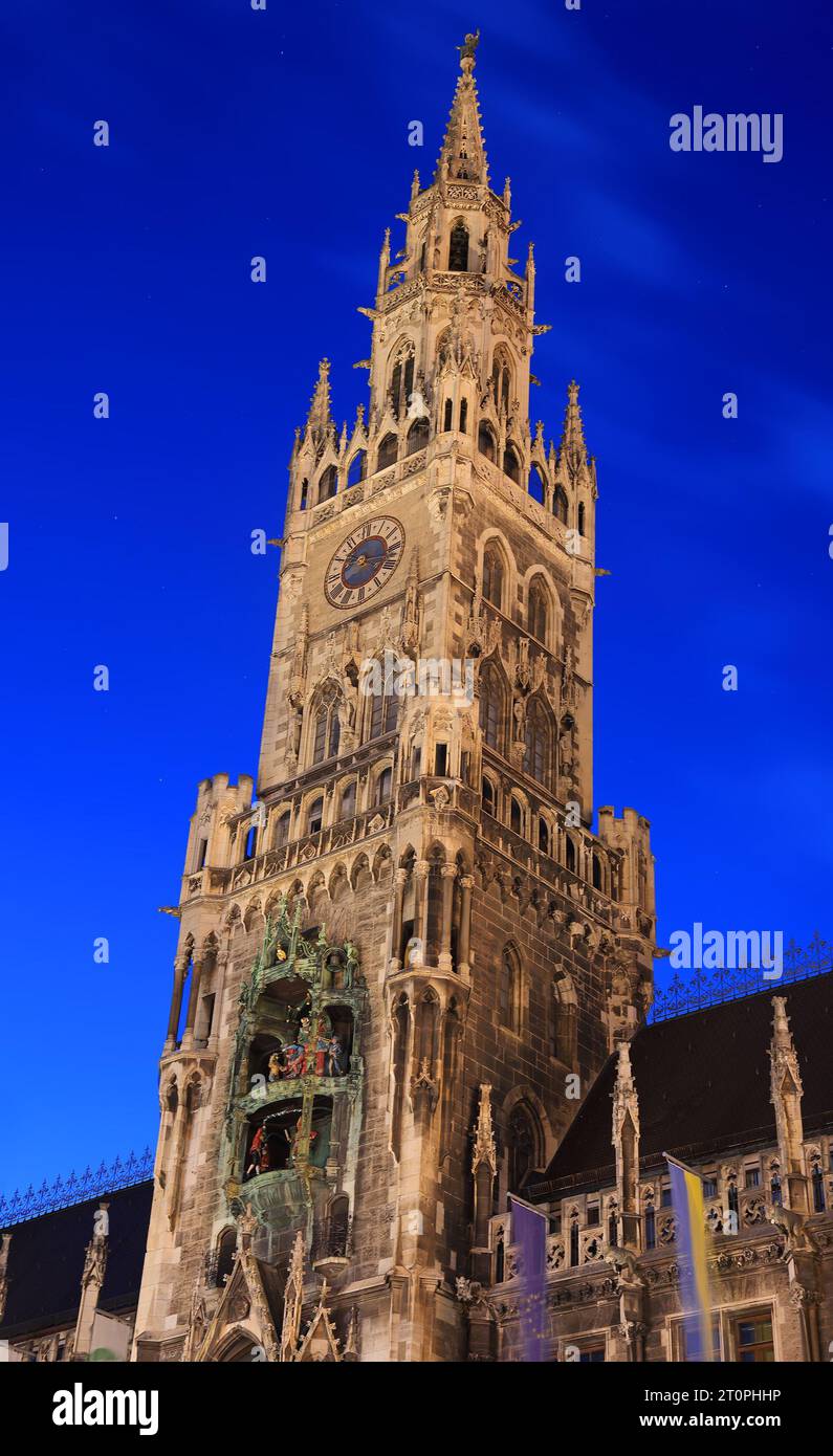 View on the town hall clock tower on Mary's square illuminated at dusk in Munich, Germany Stock Photo