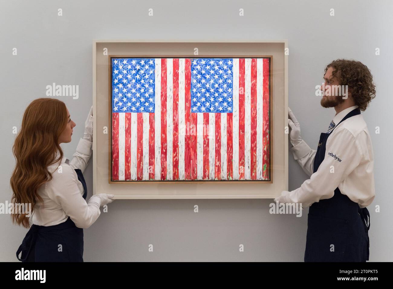 LONDON, UNITED KINGDOM - OCTOBER 06, 2023: Gallery staff members hold a painting by Jasper Johns, Flags, 1986, estimate $35 - 45 Million, during a photocall at Sotheby's auction house showcasing the highlights of Emily Fisher Landau collection in London, United Kingdom on October 06, 2023. The artworks from the collection of modern, post-war and contemporary art will be on view at Sotheby's in London between 7 and 11 October before being offered during two dedicated auctions in New York in November. (Photo by WIktor Szymanowicz/NurPhoto) Stock Photo