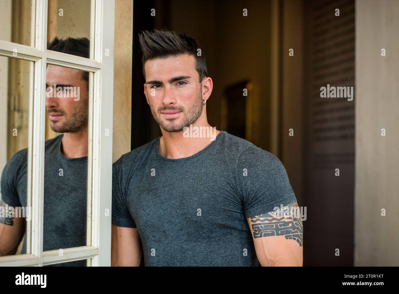 A man standing in front of a window next to another man. Photo of two ...
