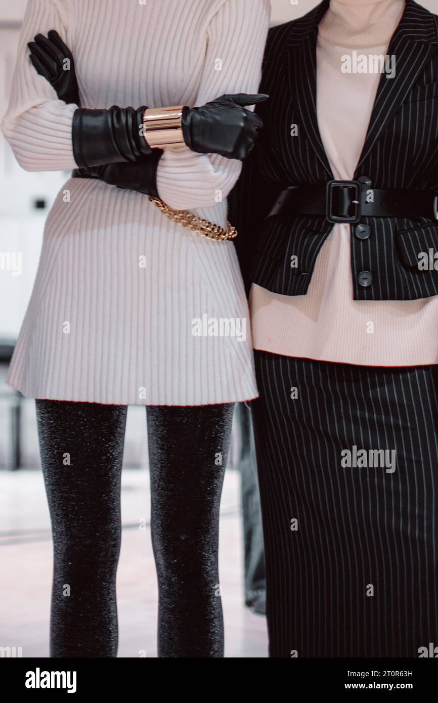 Fashion details of a knitted warm white sweater, black leather gloves