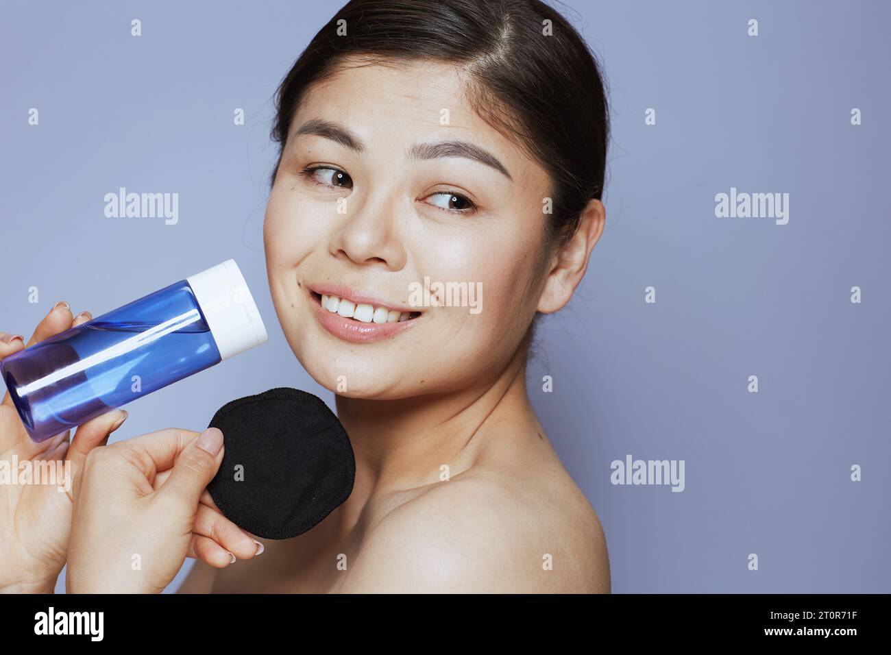 modern asian female with makeup remover and black cotton pad against blue background. Stock Photo