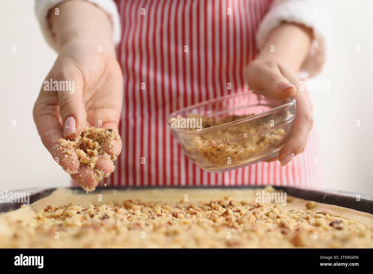 Making delicious baklava. Woman adding chopped nuts to dough, closeup Stock Photo