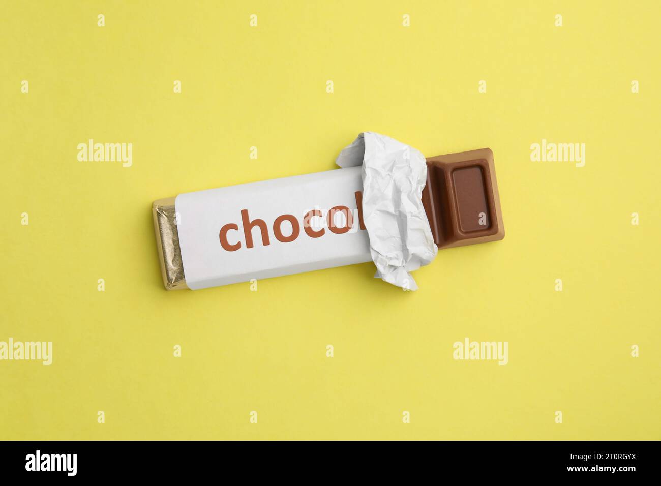 One chocolate bar in packaging on yellow background, top view Stock