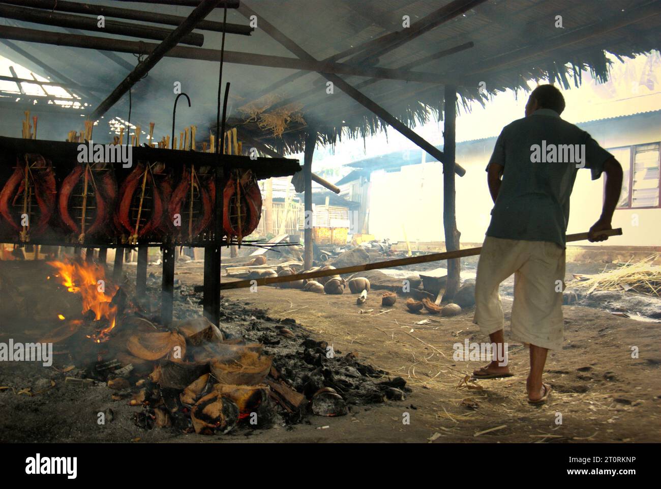 A worker maintains the equal distribution of coconut husks that are used as fuel to smoke skipjack tuna meats at a home industry in Bitung, North Sulawesi, Indonesia. The contributions of indigenous knowledge to technological innovation offer a wide array of options for management of, among others, food security, according to the 2023 report of Intergovernmental Panel on Climate Change (IPCC). Popularly known as cakalang fufu, the smoked tuna fish is considered an exotic indigenous food, and could become an alternative solution to deal with climate change impacts on the ocean. Stock Photo