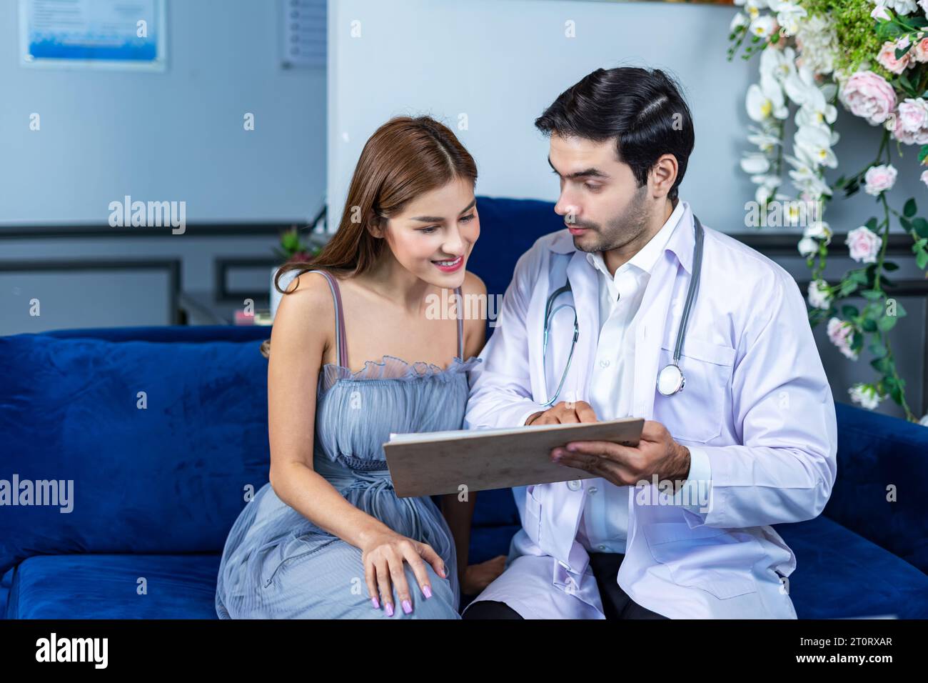Physician men talking and looking at X Ray film with woman patient at clinic. Doctor discussing with patient in medical room at hospital. Stock Photo