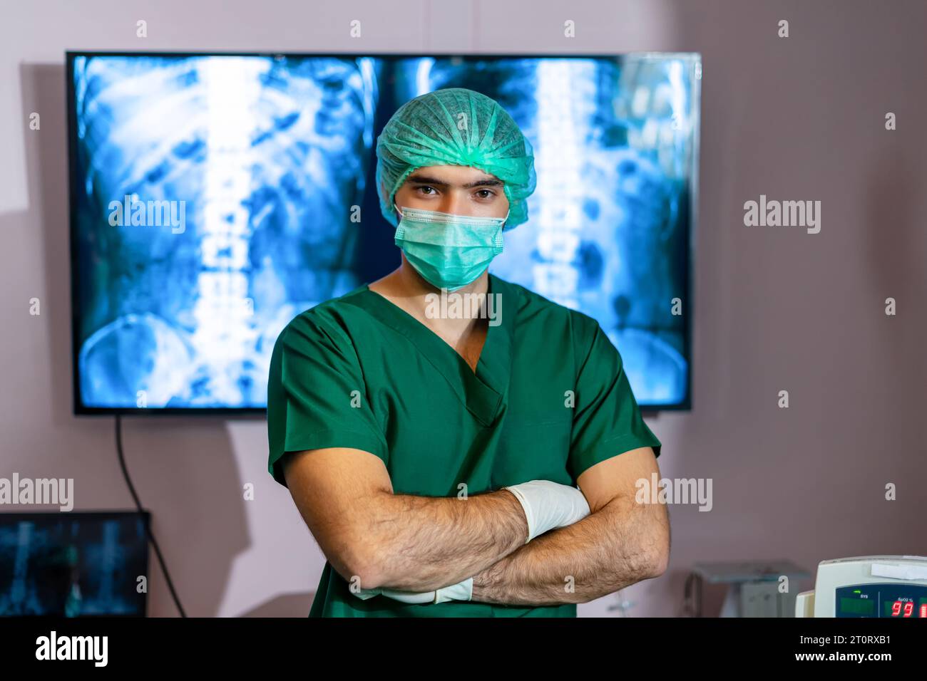 Man wearing green surgical gown standing with arms crossed in operating room, show readiness start surgery for patients who waiting for treatment. Vir Stock Photo