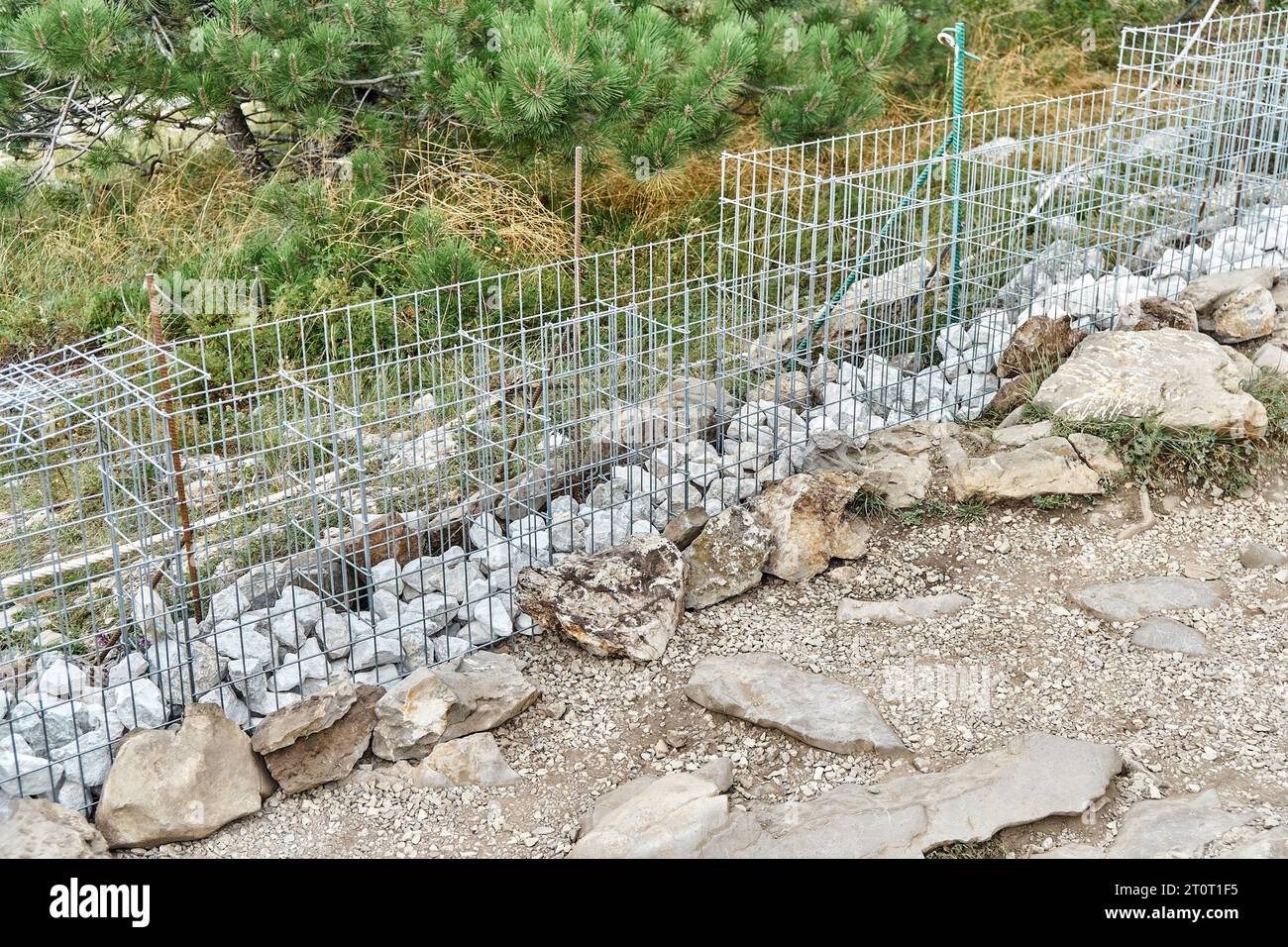Gabion building process. Unfinished gabion building of rocks and metal