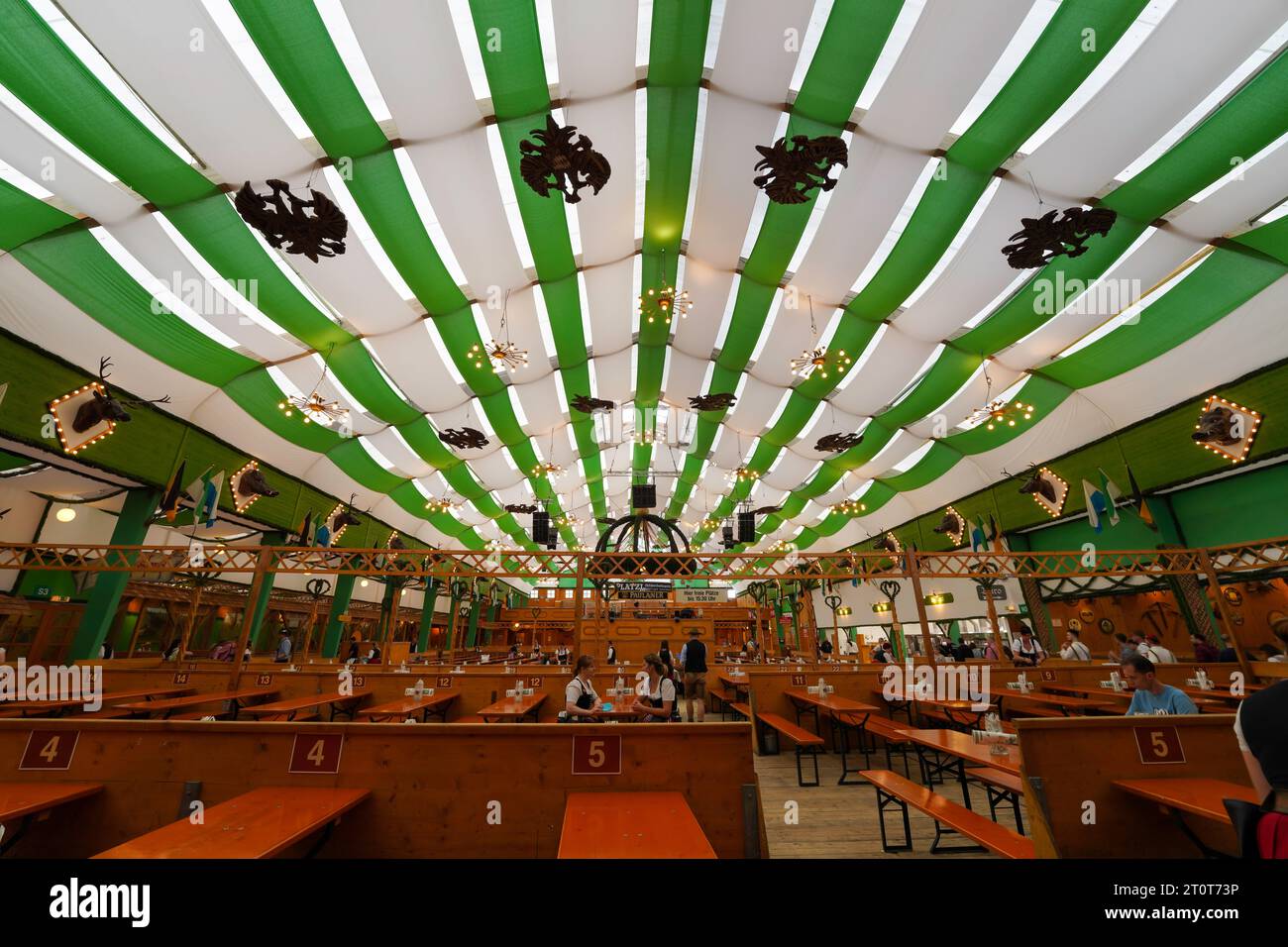 Munich, Germany, EU - September 18, 2023. Oktoberfest Munich Beer Tent interior with decorations, people drinking, eating in dirndls and lederhosen. Stock Photo