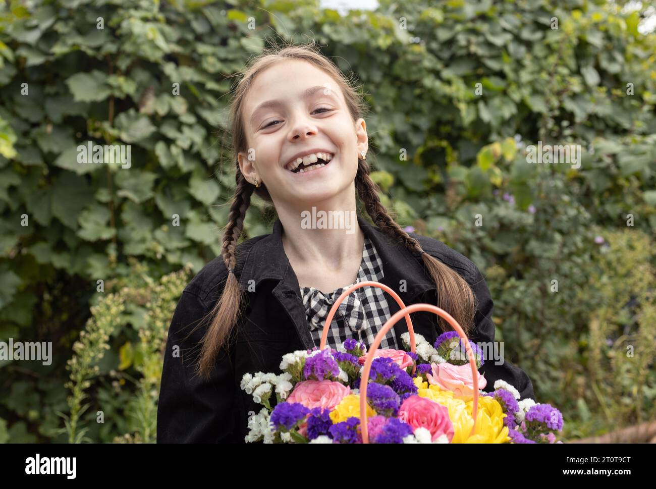 portrait of a cheerful laughing girl 7-8 years old with a bouquet of flowers in her hands. Happy childhood, joyful emotional children, positive child. Stock Photo