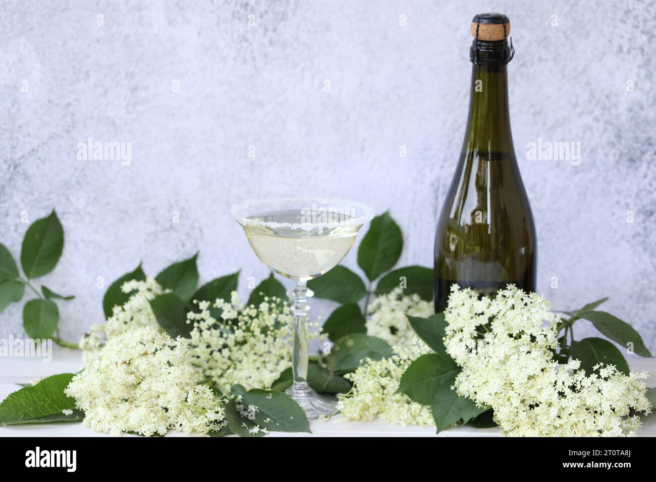 Glass and bottle of champagne with elderflower liqueur. On grey background with copy space Stock Photo