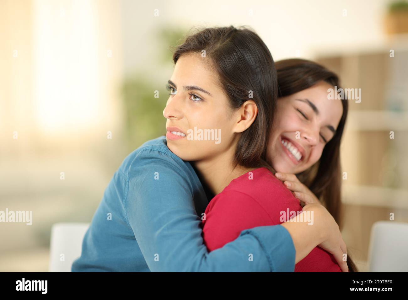 Happy woman hugging a false friend in the living room at home Stock Photo
