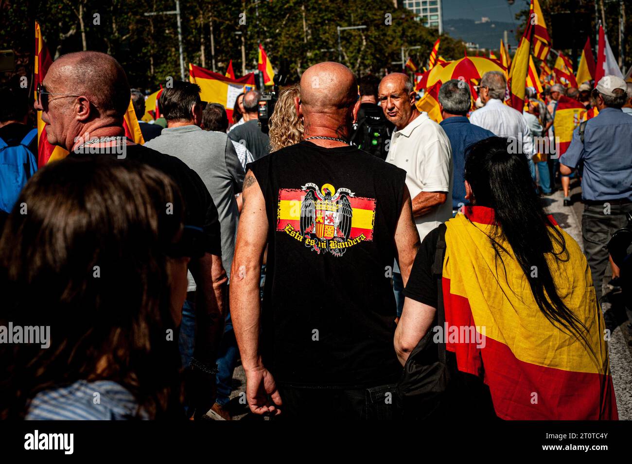 Barcelona, Spain. October 8, 2023, Barcelona, Spain: A man walks carrying a Francoist flag sign  on his shirt as people demonstrate in Barcelona against the plans of Spain's provisional government to agree with Catalan forces on a possible amnesty law that would include former Catalan president Carles Puigdemont. Credit: Jordi Boixareu/Alamy Live News Stock Photo