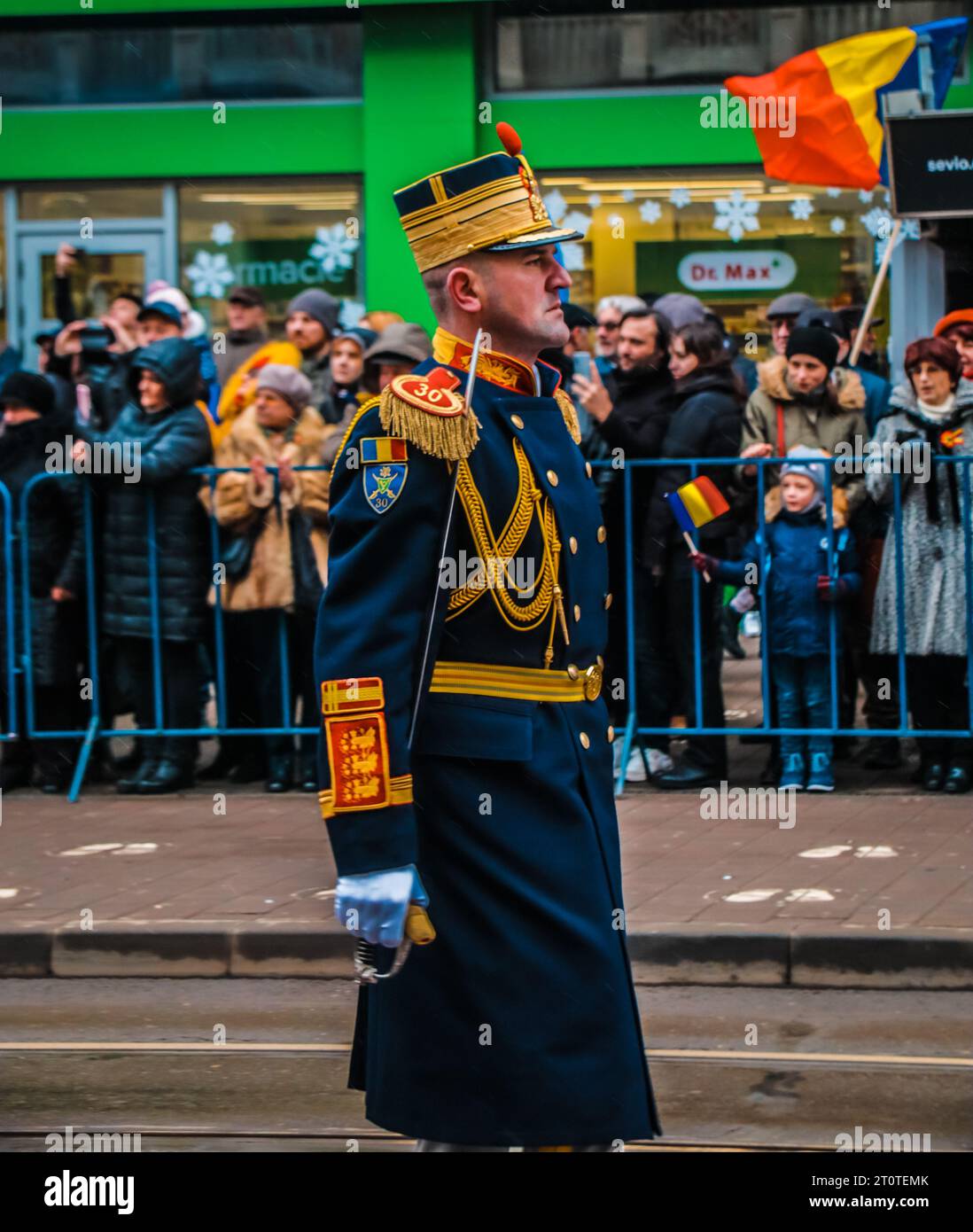 A Caucasian man in military uniform stands in a city street surrounded by a diverse crowd of pedestrians Stock Photo