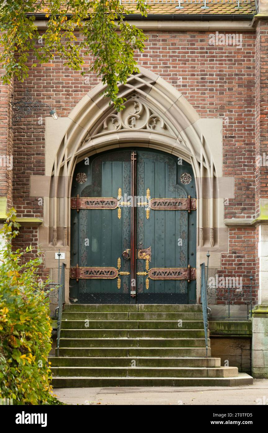 A brick building with two green doors featuring detailed and ornate designs Stock Photo