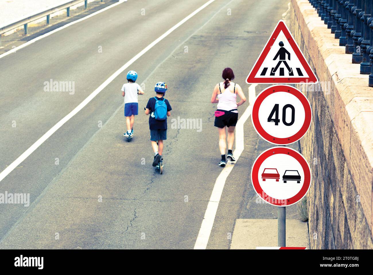Signs on the road, running woman, kids on scooters Stock Photo