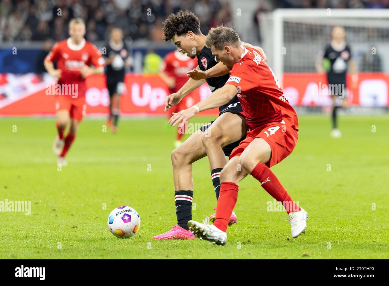 08 October 2023, Hesse, Frankfurt/Main: Soccer: Bundesliga, Eintracht Frankfurt - 1. FC Heidenheim, Matchday 7, Deutsche Bank Park. Ignacio Ferri Julia (M) of Eintracht Frankfurt and Tim Siersleben (r) of Heidenheim fight for the ball. Photo: Jürgen Kessler/dpa - IMPORTANT NOTE: In accordance with the requirements of the DFL Deutsche Fußball Liga and the DFB Deutscher Fußball-Bund, it is prohibited to use or have used photographs taken in the stadium and/or of the match in the form of sequence pictures and/or video-like photo series. Stock Photo