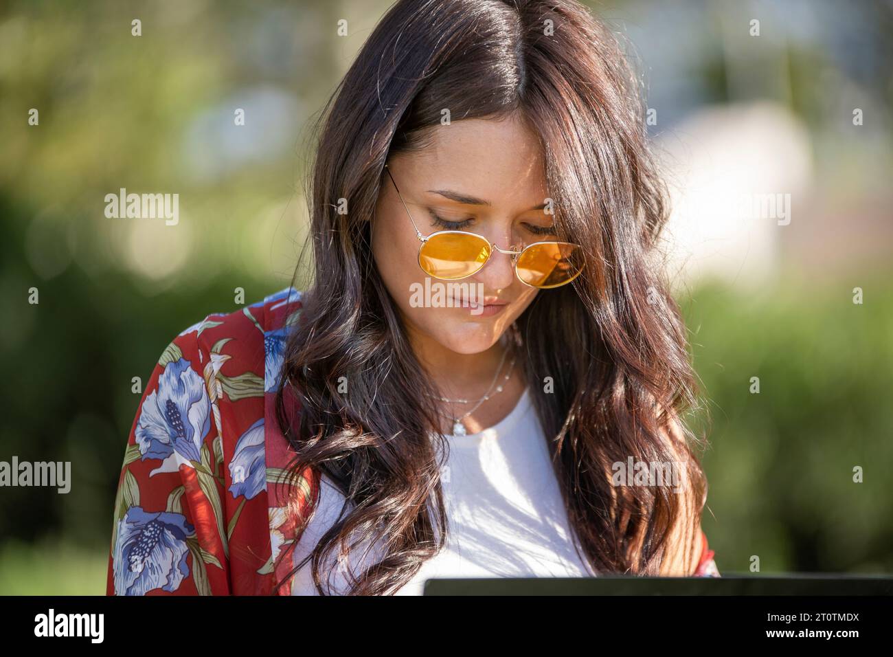 Close-up view of a woman with sunglasses using a laptop outdoors. Technology concept. Stock Photo