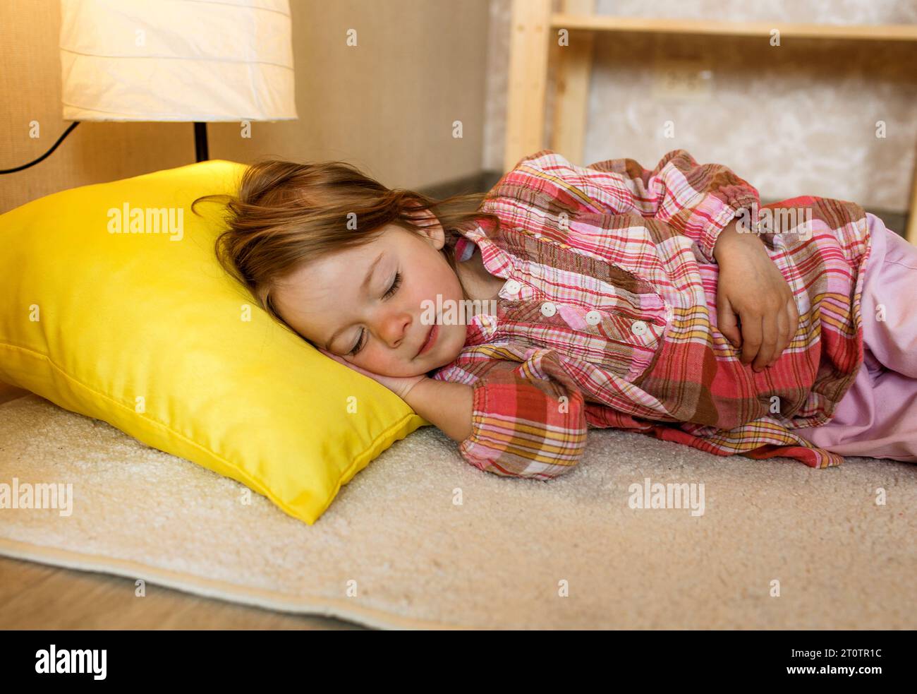 A small child sleeps on the floor at home Stock Photo