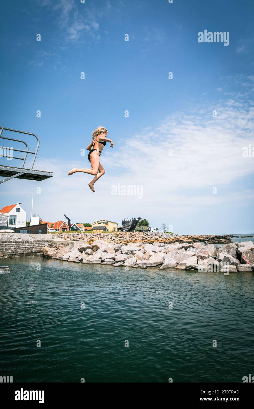 Woman Jumping Into Ocean From High Dive in Denmark Stock Photo