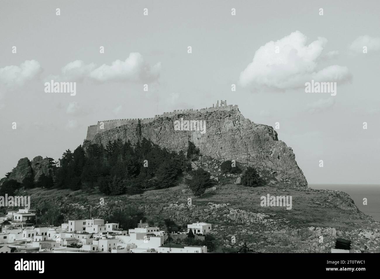 View from Lindos of the Acropolis of Lindos fortress on top of a mountain in black and white Stock Photo