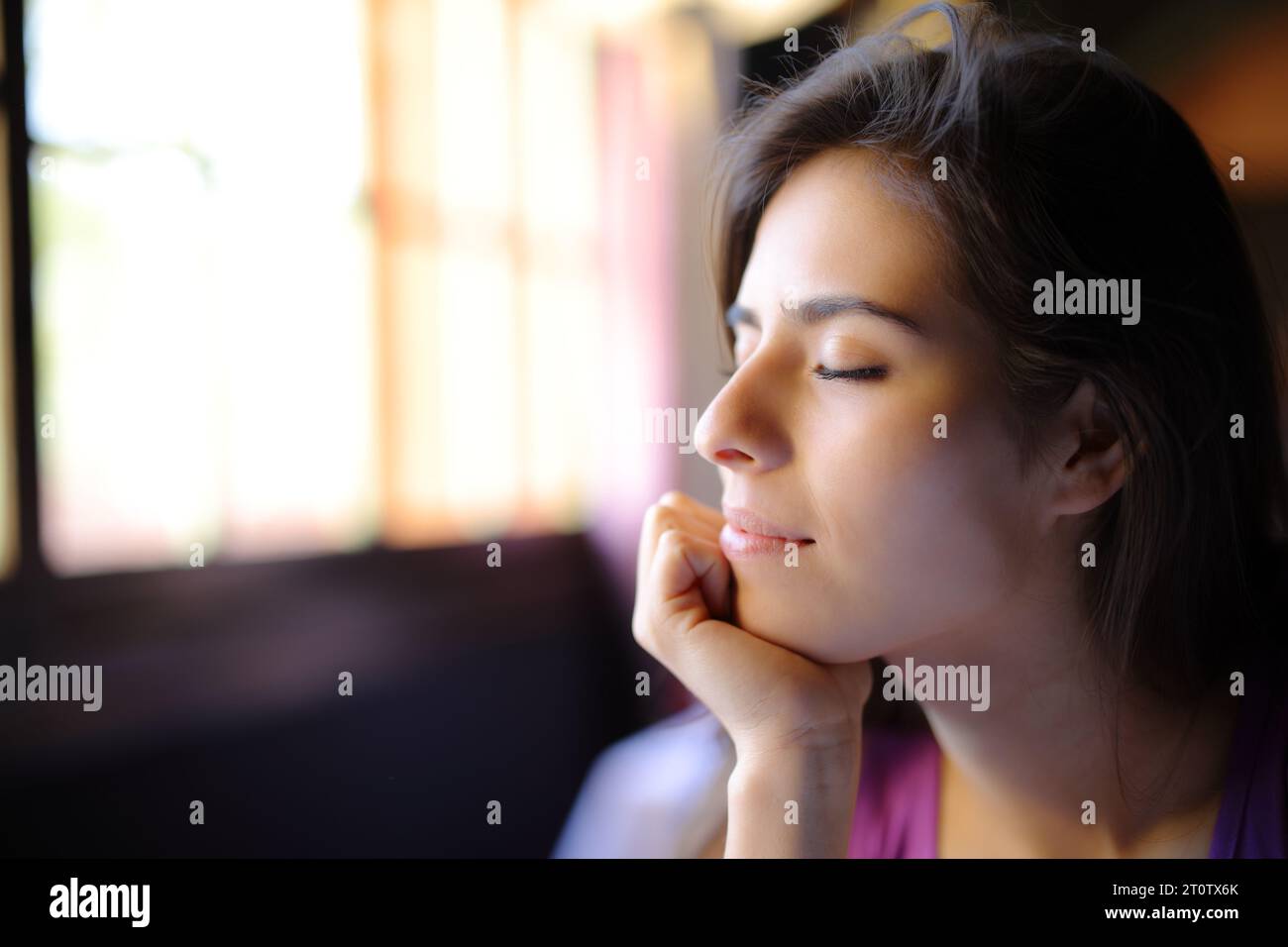 Relaxed woman beside a window with closed eyes at home Stock Photo