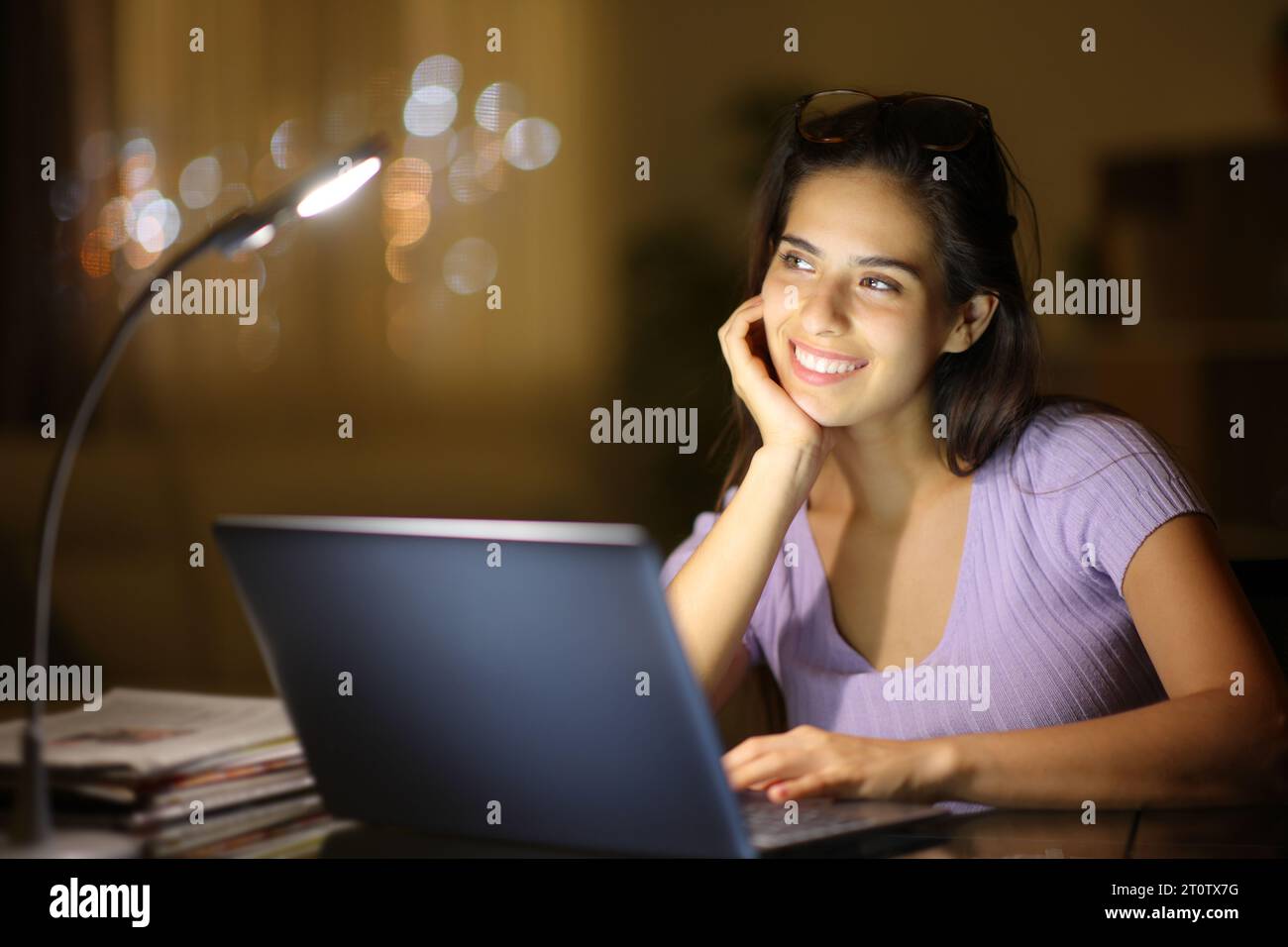 Happy woman with a laptop dreaming in the night at home Stock Photo