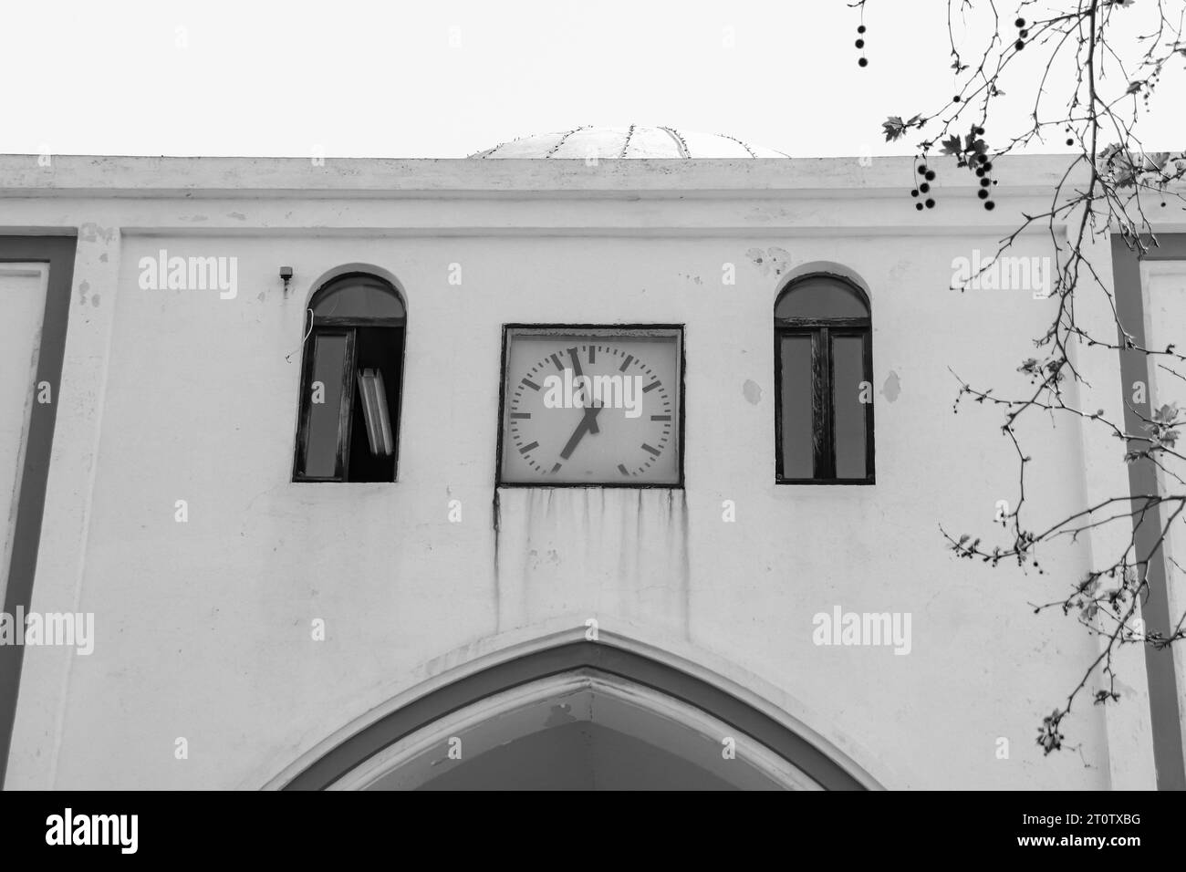 Gate wall of Rhodes city New Market (Nea Agora) with a clock showing the time of day in black and white Stock Photo