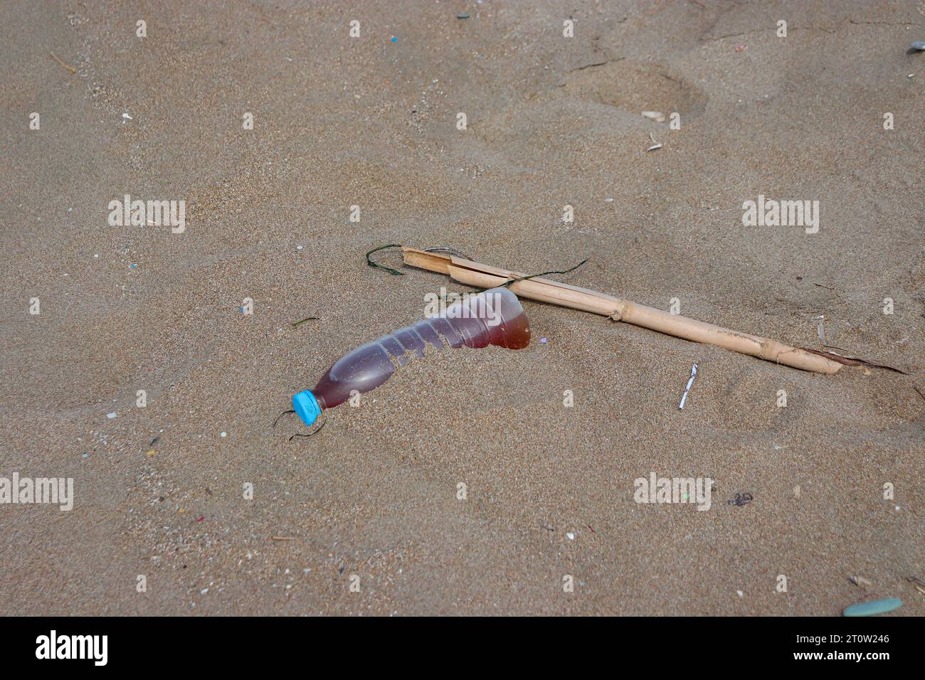 Dirty water bottle thrown on beach sand creating trash and pollution