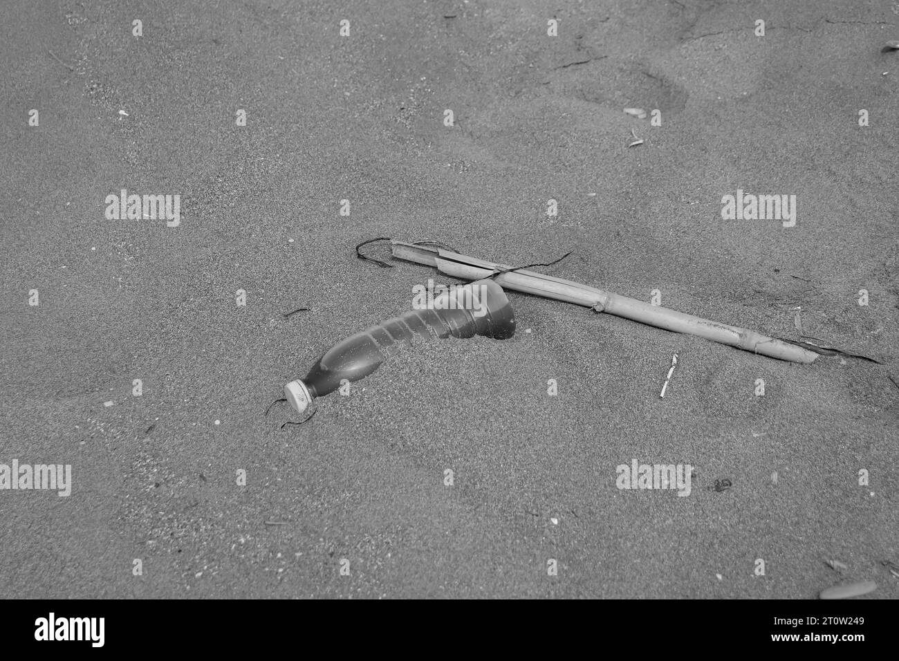 Dirty water bottle thrown on beach sand creating trash and pollution near the ocean in nature. World environment day, ecological, pollution concept Stock Photo