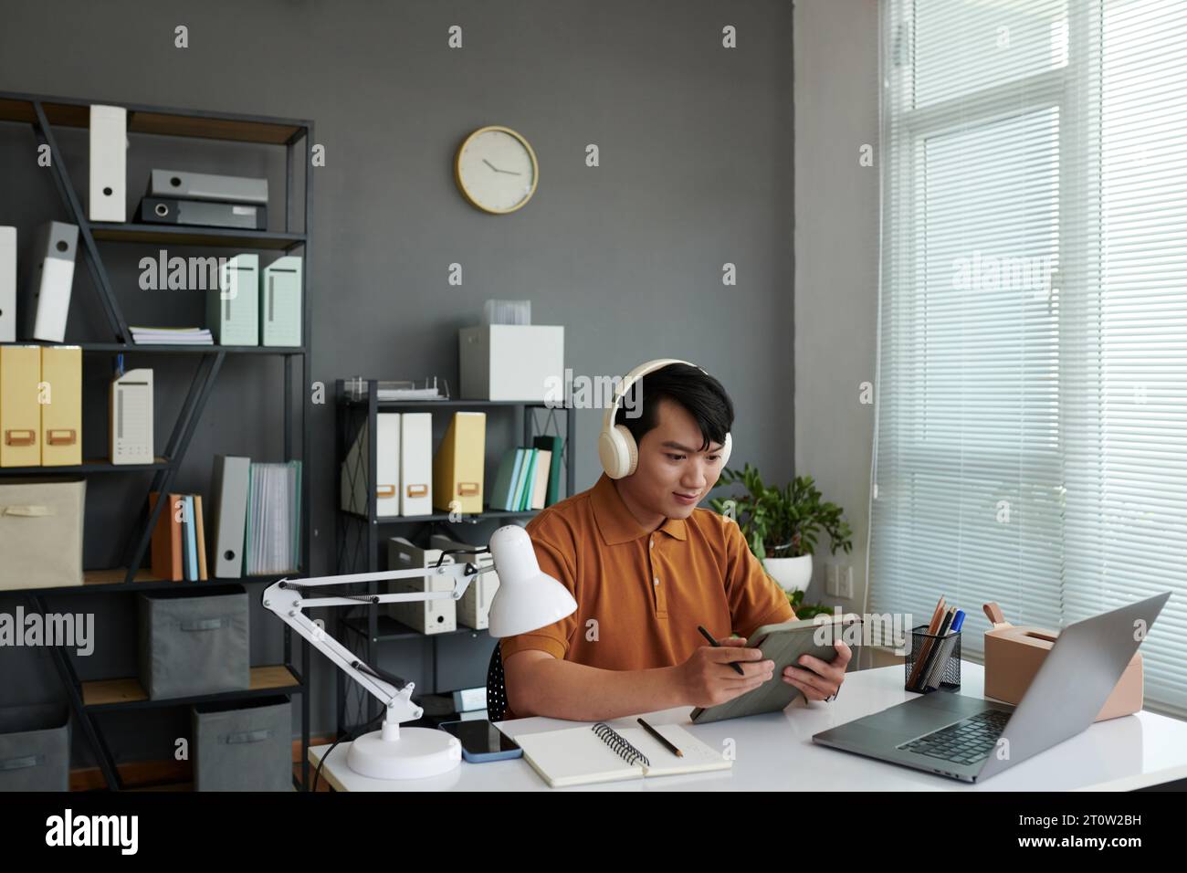 Young Asian developer working on tablet computer in his home office Stock Photo