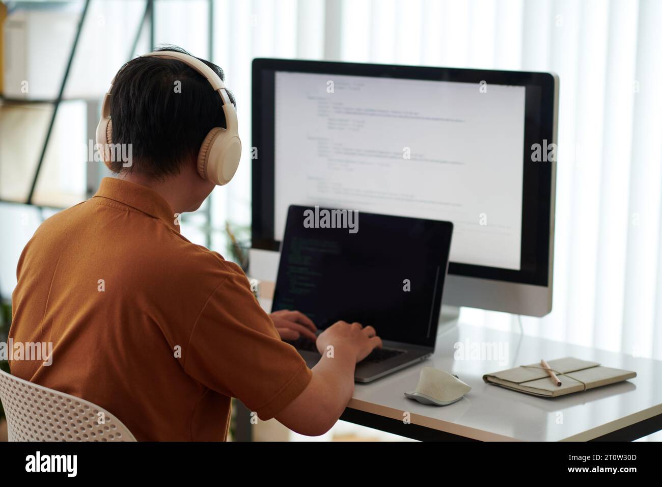 Developer wearing headphones when testing new software on laptop Stock Photo