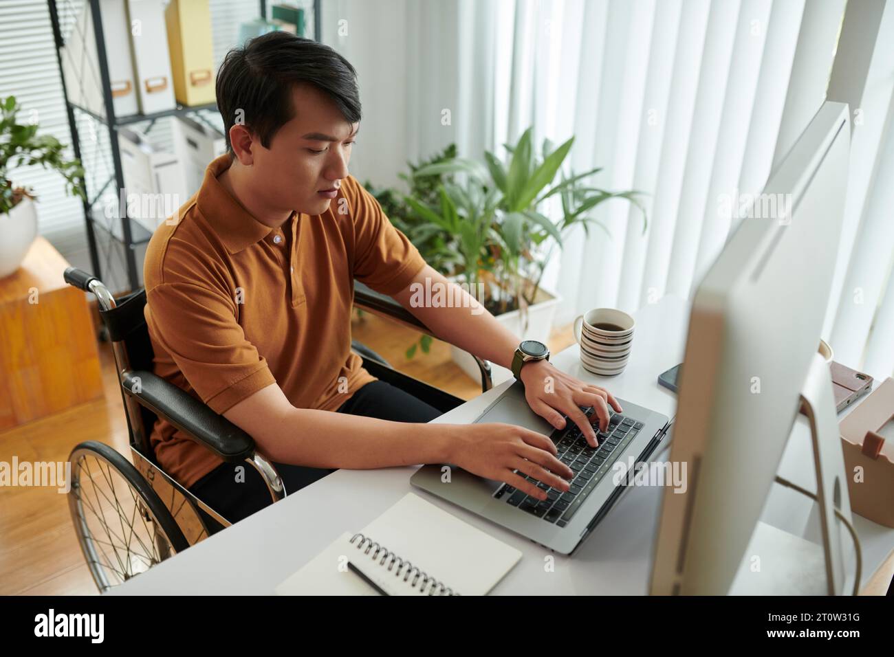 Concentrated young man with disability learning programming Stock Photo