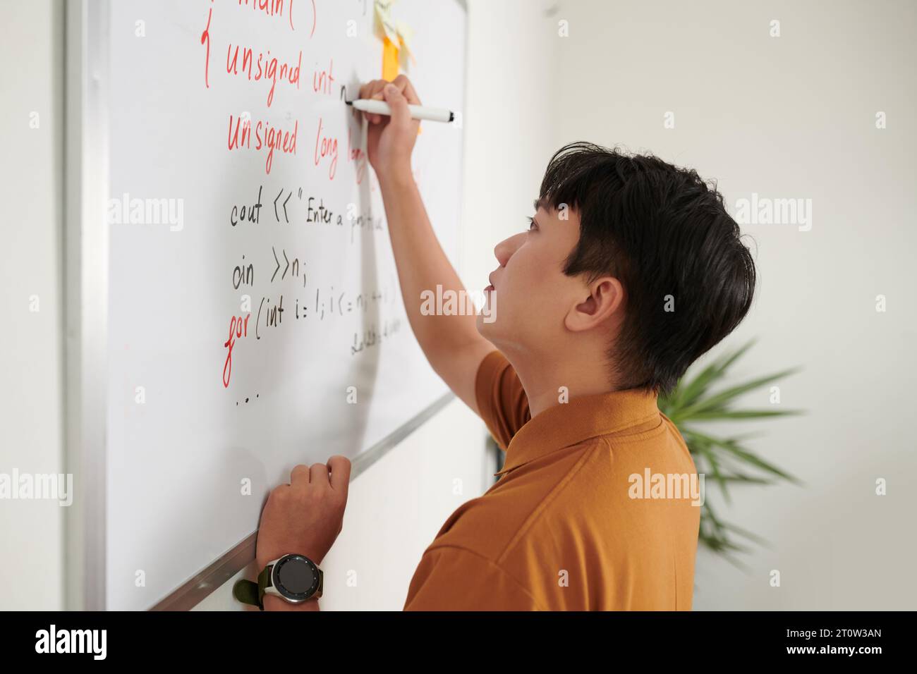 Developer writing programming code on whiteboard when trying to solve problem Stock Photo