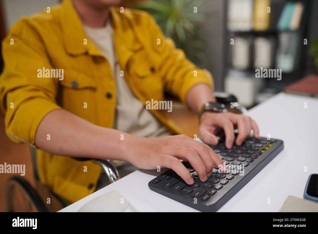 Closeup image of man with disability working on computer in office, answering e-mails and coding Stock Photo