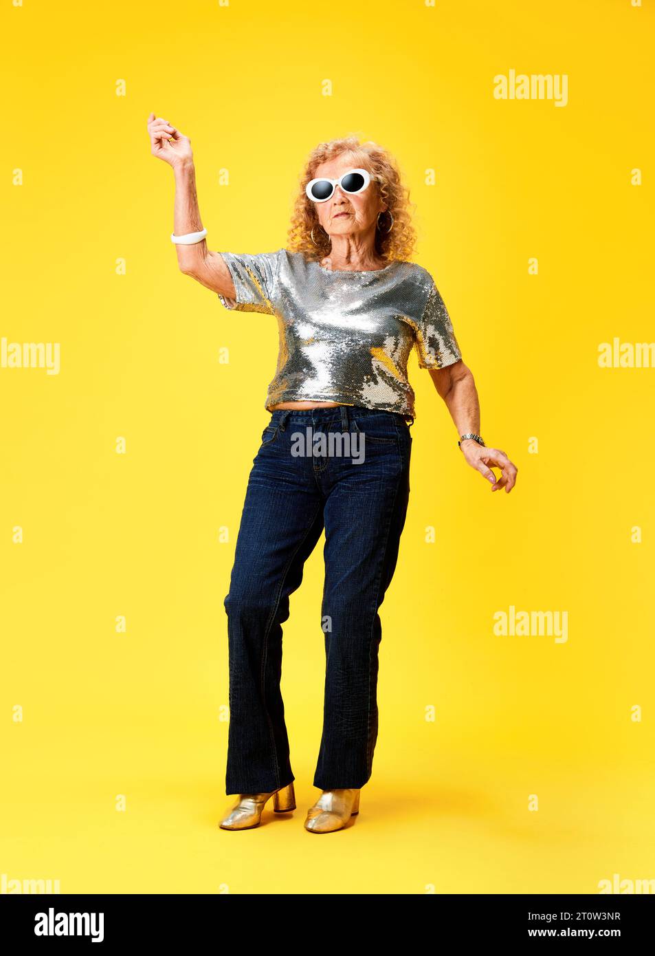 Fulllength of stylish senior woman in silver sparkling top and jeans