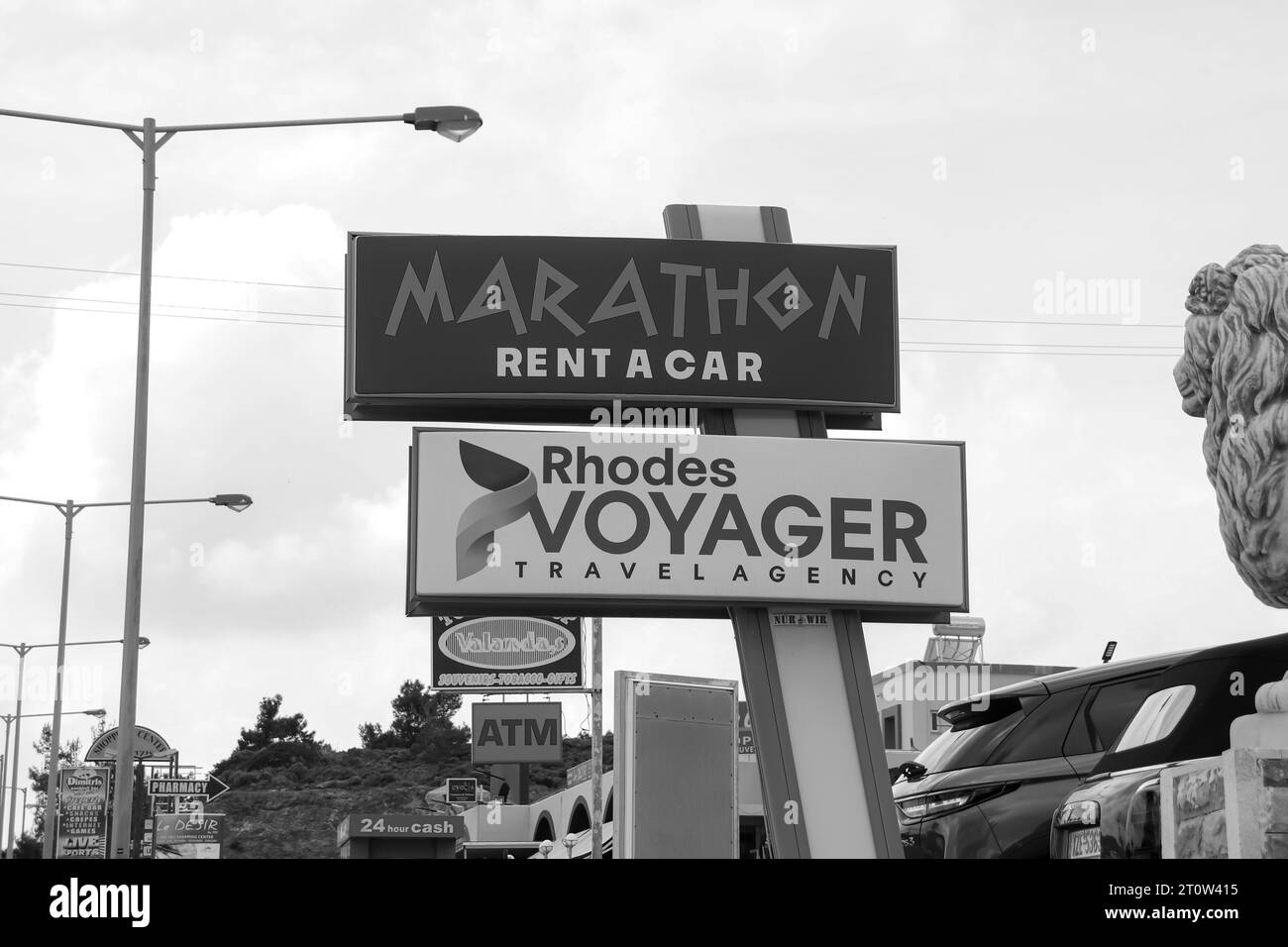 Marathon Rent a Car business and Rhodes Voyager travel agency office sign informing tourist people of store location in black and white Stock Photo