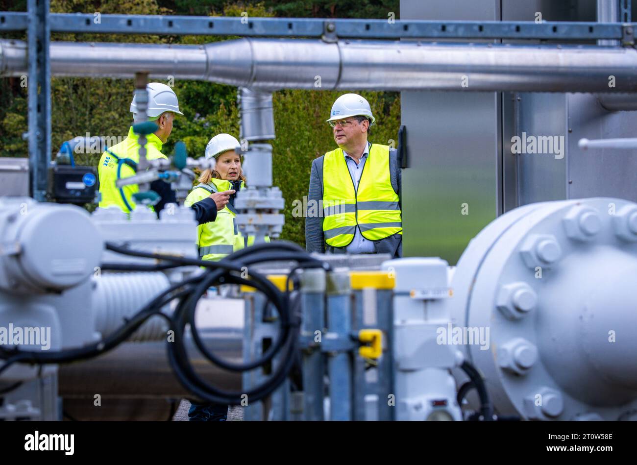 09 October 2023, Mecklenburg-Western Pomerania, Kraak: Reinhard Meyer (r, SPD), Mecklenburg-Western Pomerania's Minister of Economics, Tourism and Transport, inspects Mecklenburg-Western Pomerania's only gas storage facility with storage manager Eva-Maria Diederichs and Matthias Boxberger (l), CEO of HanseWerk. The cavern storage facility, which measures seven by four and a half kilometers and has a volume of up to 300 million cubic meters, secures the supply of natural gas to gas customers in northern Germany. The storage facility is located in an extensive salt dome beneath the surface of th Stock Photo