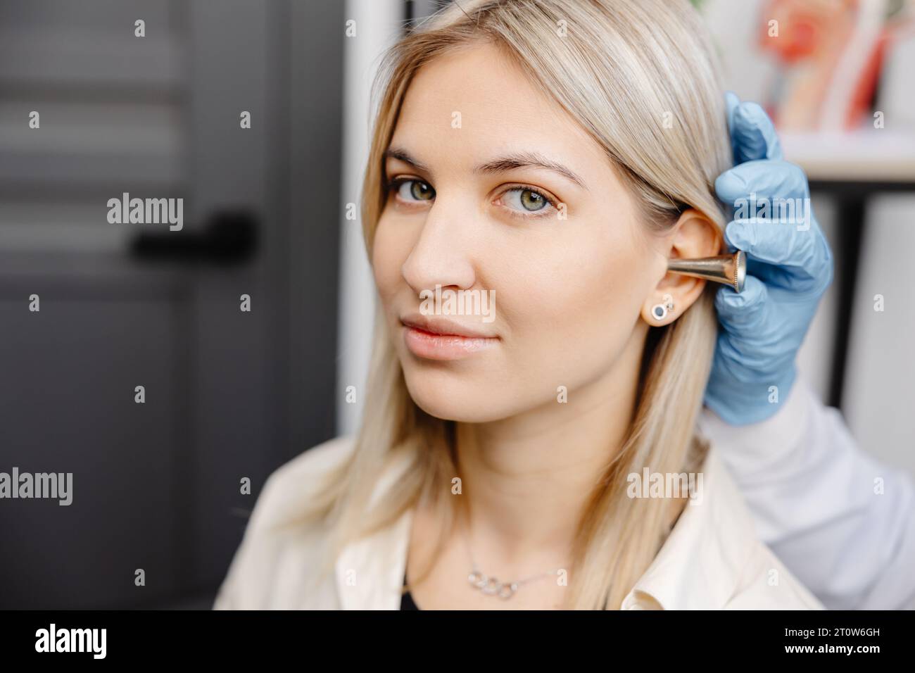 Otolaryngologist doctor checking young woman's ear using otoscope or