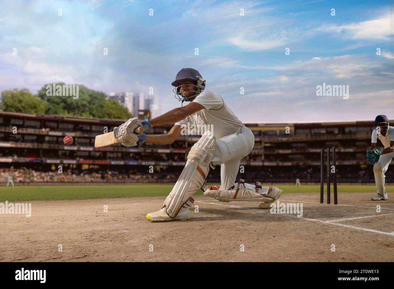 Cricketer batsman hitting a sweep shot during a cricket  match on the pitch Stock Photo