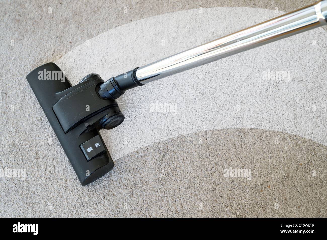 Vacuum cleaner cleaning a streak on a carpet to eliminate dirt and allergy causing house dust mites, copy space, selected focus, narrow depth of field Stock Photo