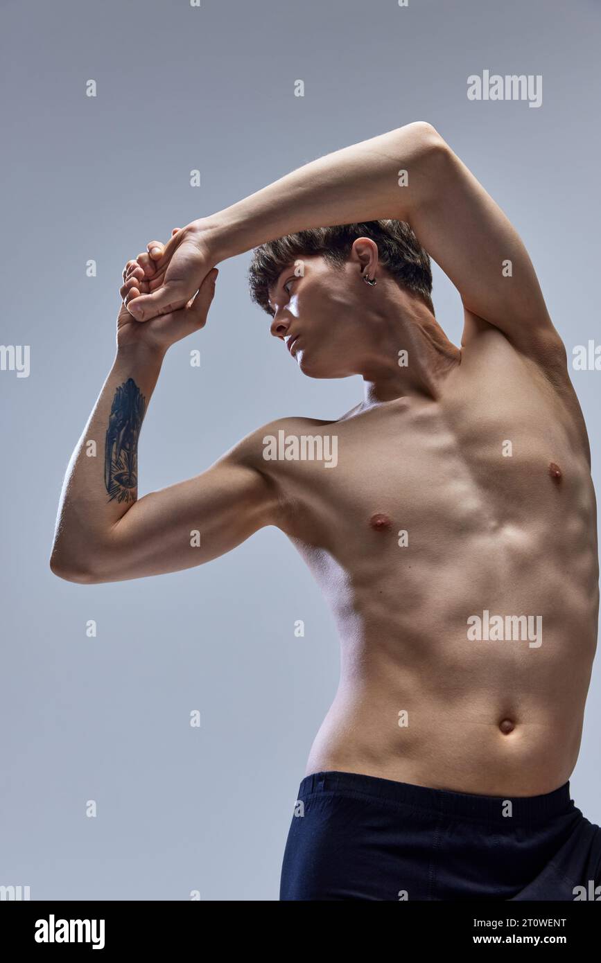 Handsome man with athletic body posing looking away and raising hands ...