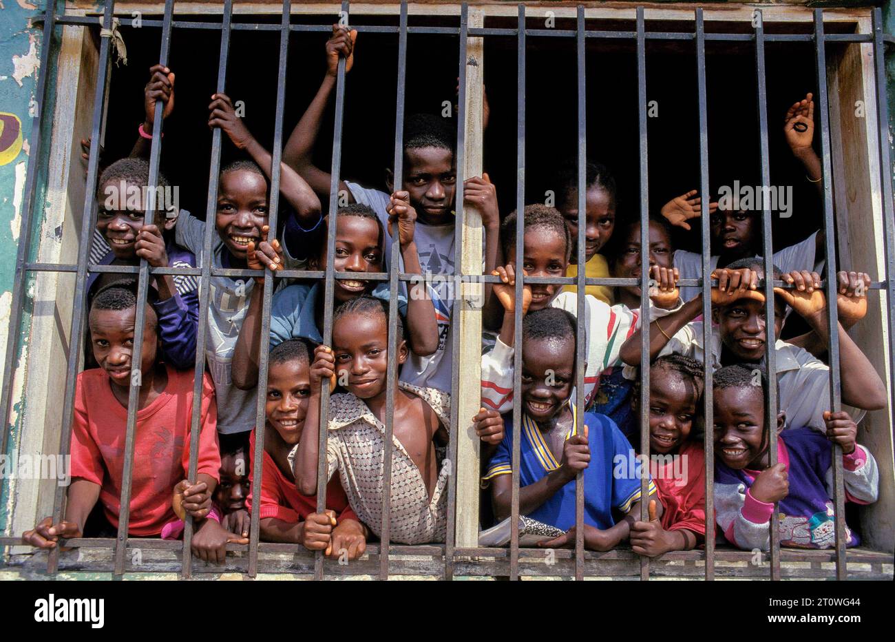 Liberia, schoolchildren in a refugee camp, standing behind the bars of a schoolwindow in a displaced camp. Stock Photo