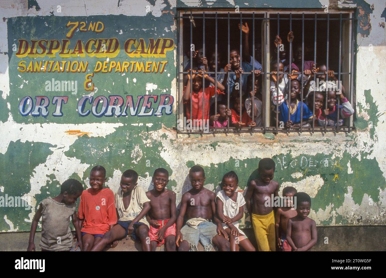 Liberia, schoolchildren standing behind the bars of a schoolwindow in a displaced camp. Stock Photo