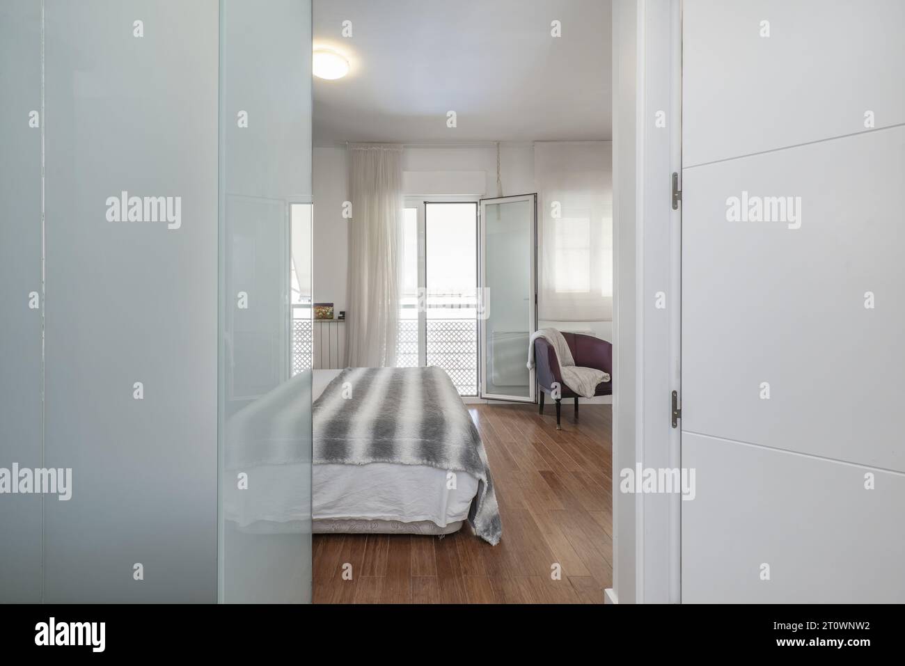 Double bedroom en suite with a balcony with views, bathroom with separate shower and dressing room behind a mirror Stock Photo
