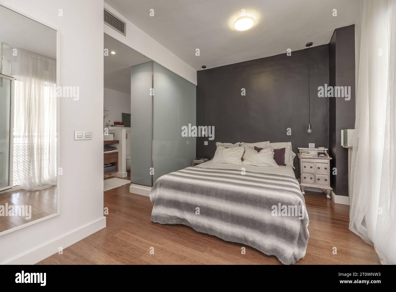Double bedroom en suite with two-tone walls, wooden floors, bathroom with shower Stock Photo