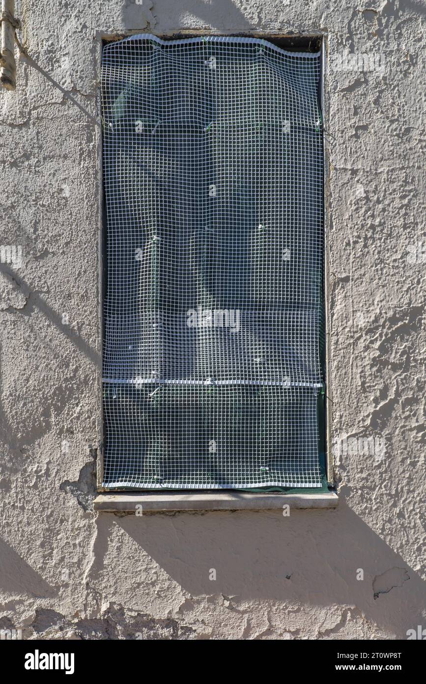 A wall with a window with white plastic grille Stock Photo