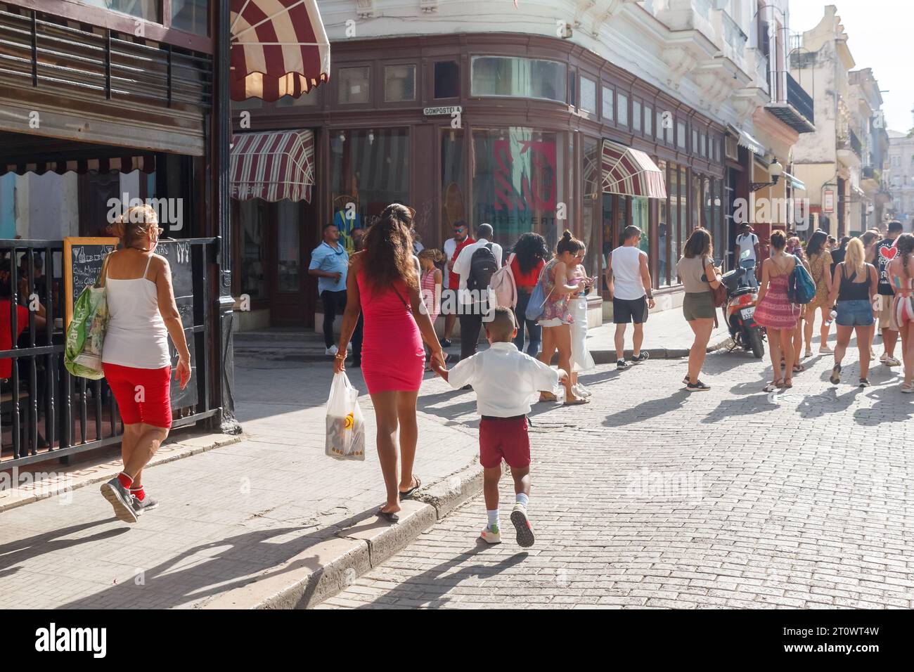 Cuban people in their usual day routines walk in a cobblestone pedestrian boulevard in Old Havana. Stock Photo
